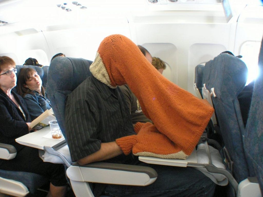 2016 image of person on plane typing into laptop wearing a knitted garment that obscures the screen and their hands