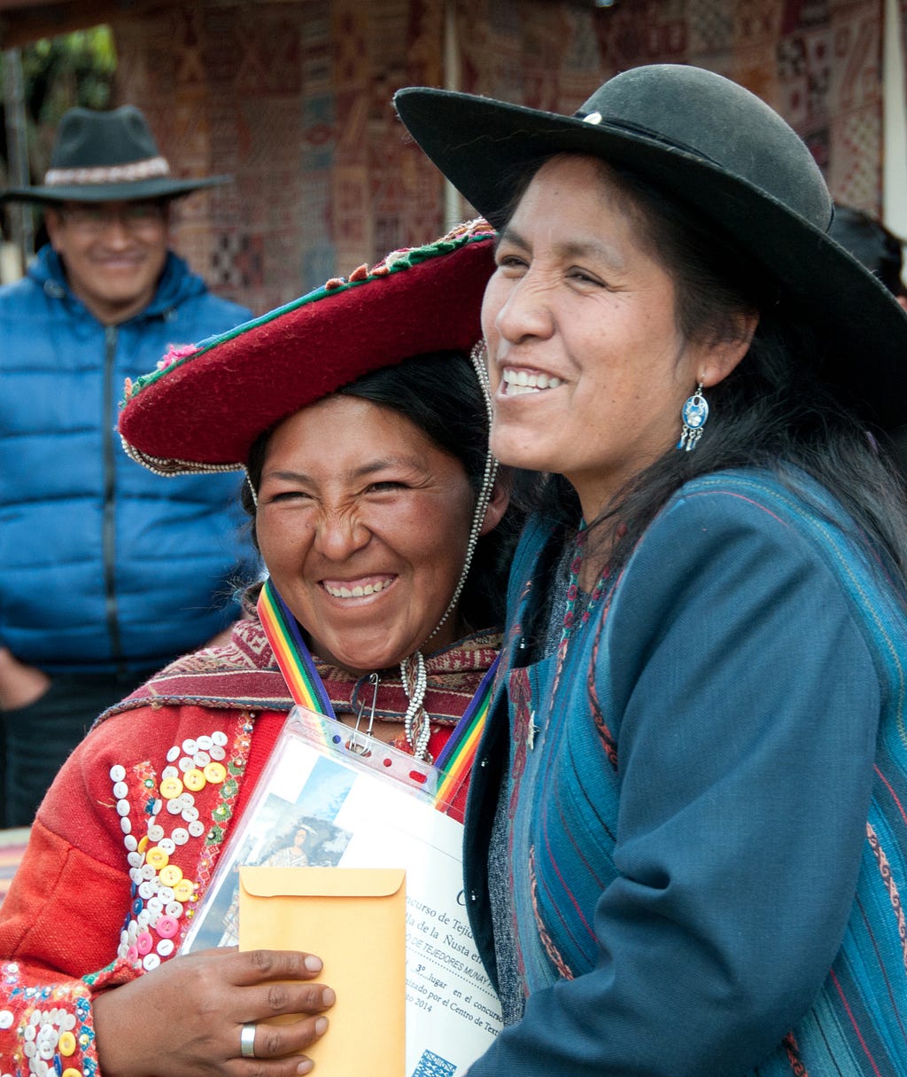 Nilda Callañaupa (right) congratulates a winning weaver at the Peru Weavers Awards in Chinchero near Cusco, Peru.(© April Orcutt. All Rights Reserved)