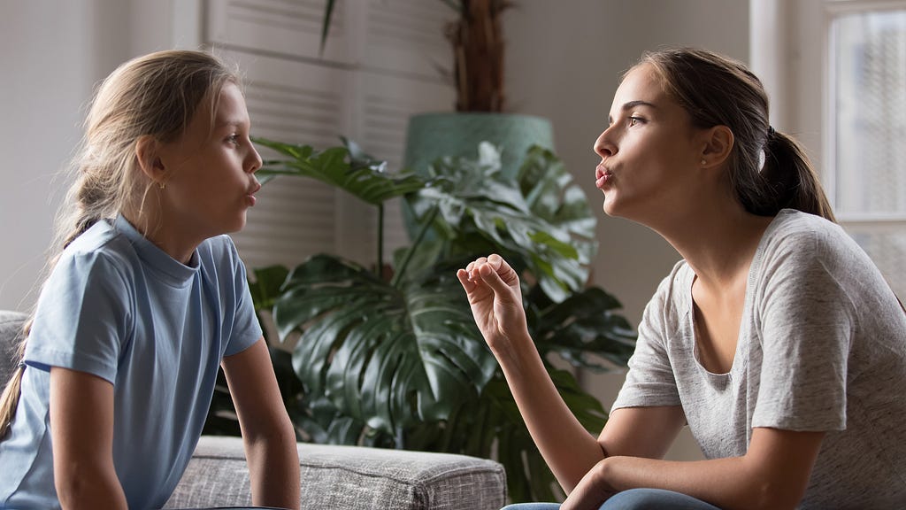 Young mom do pronunciation exercises with daughter