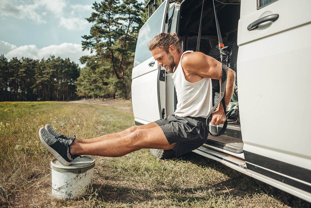 Man doing fitness in the door of a campervan