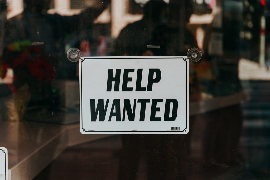 Image of a store sign with the words “Help Wanted.”