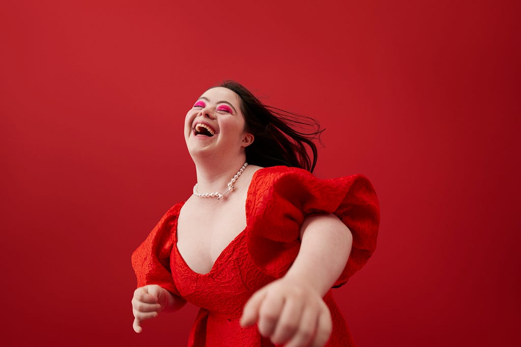 Young woman laughing against red background