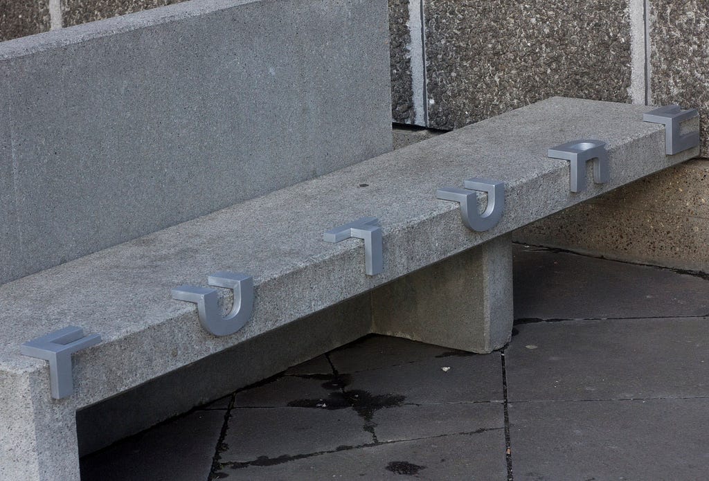 Concrete bench with protruding metal letter wrapped at the edge of the base of the bench that spells out FUTURE