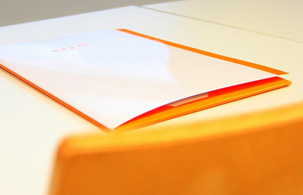 An orange chair and orange portfolio with a blank cover page.