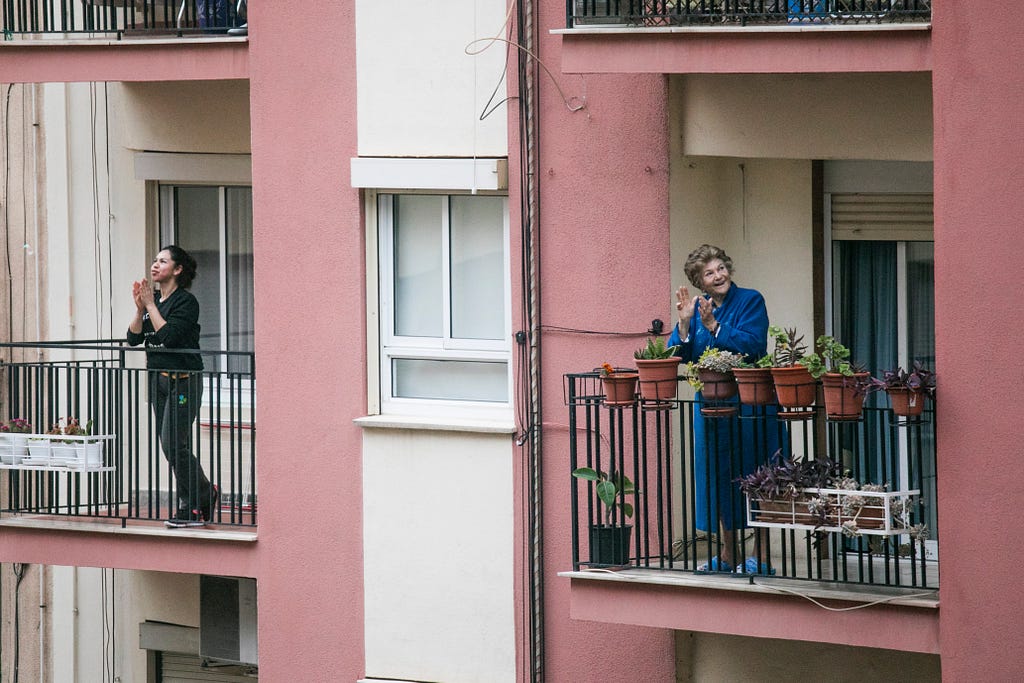 A photo of two neighbors on their balconies, clapping, during Coronavirus quarantine.