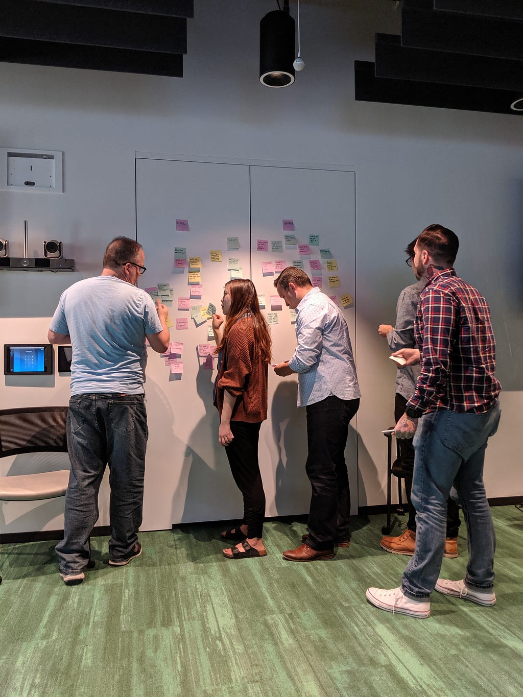 Team members hanging post-it notes on the wall during a monthly retrospective meeting
