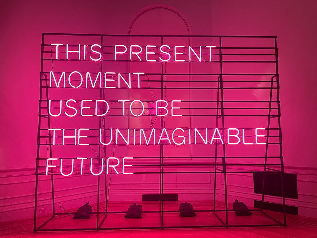 THIS PRESENT MOMENT USED TO BE THE UNIMAGINABLE FUTURE — in hot pink flourescent lights