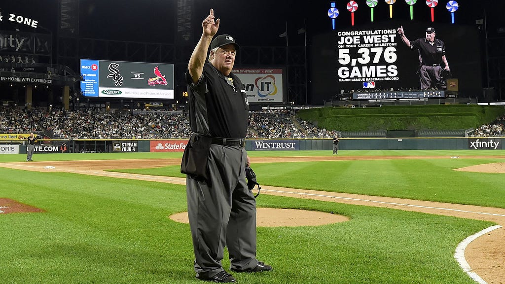 Umpire Joe West acknowledges the crowd as they applaud for the announcement honoring West breaking the record for most games umpired