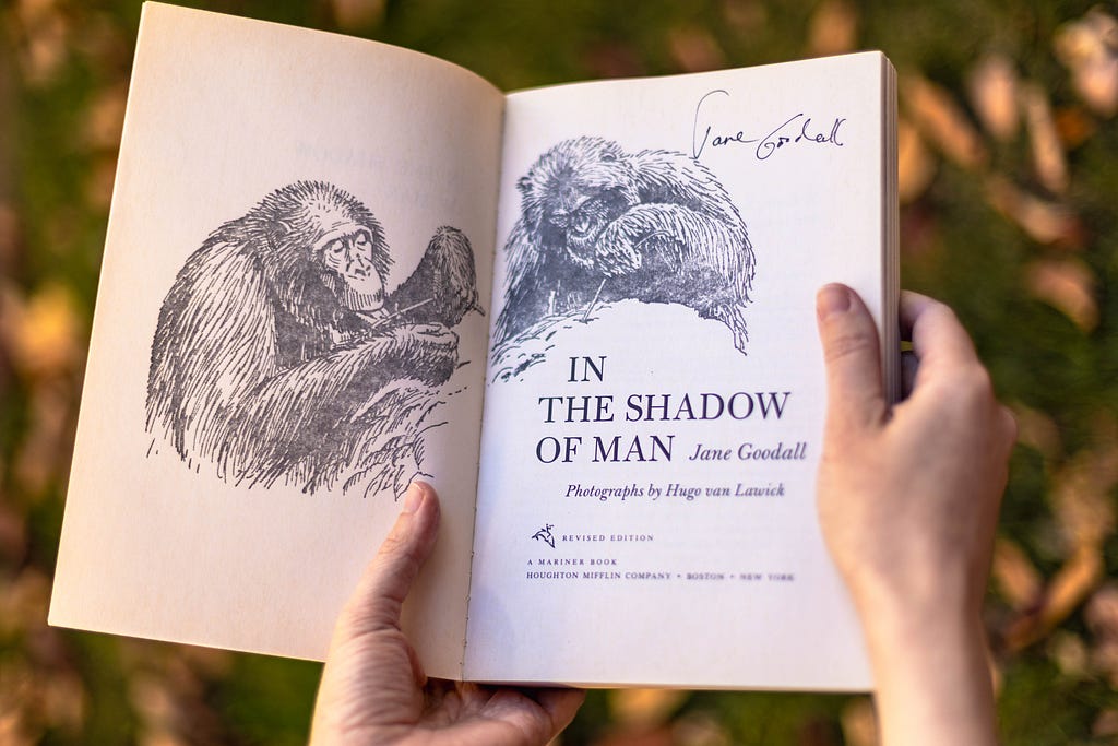 The front page of Jane Goodall’s “In the Shadow of Man” opens to review Jane Goodall’s signature above an illustration of a chimpanzee.