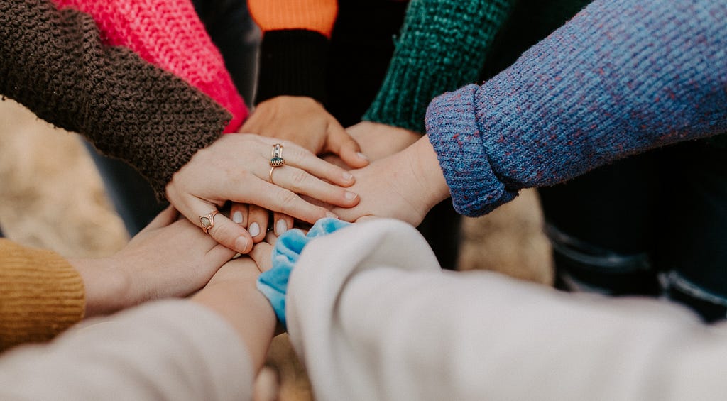 A group of people bringing their hands together, signifying unity