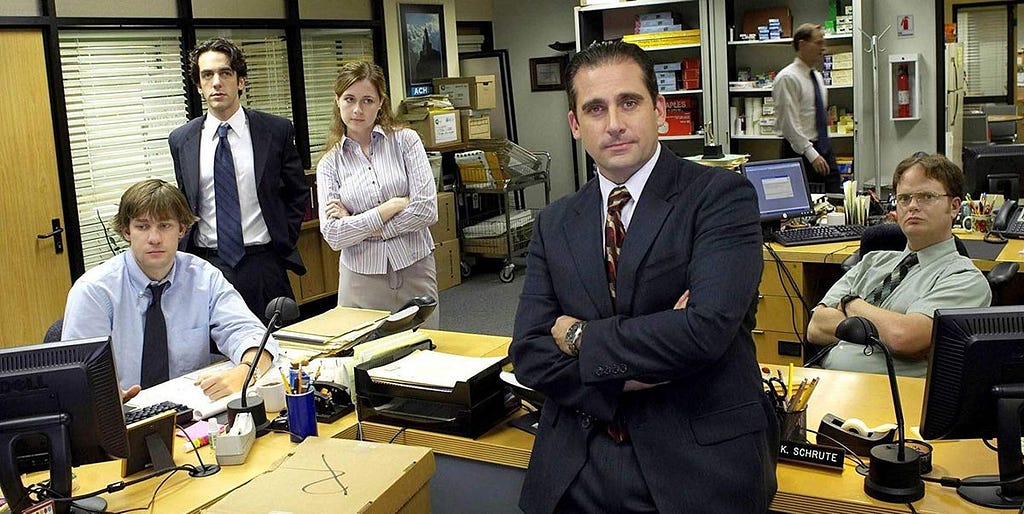 A group of employees in suits standing and sitting around an office
