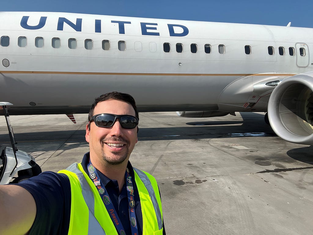 Alex posing with United aircraft on the runway.