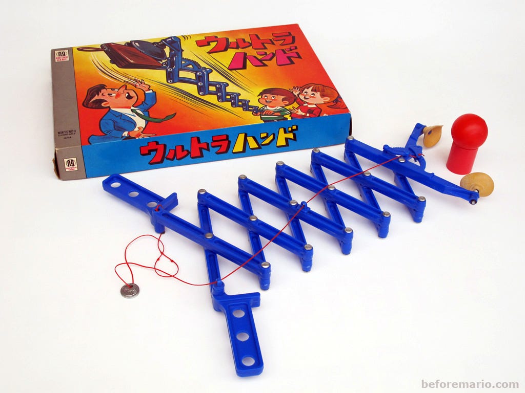 A plastic toy with two handles that can be pushed or pulled to extend or retract the two rubber clamps grasping an object.