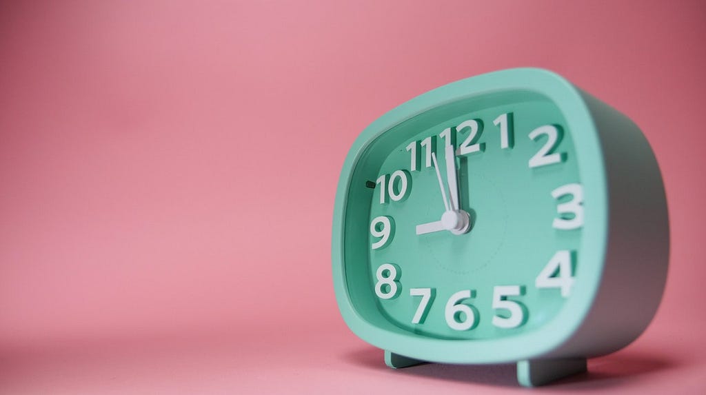 Mint green alarm clock with pink background.