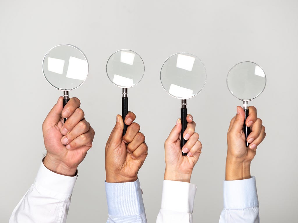 Four hands holding magnifying glasses. Photo by solidcolours/Getty Images