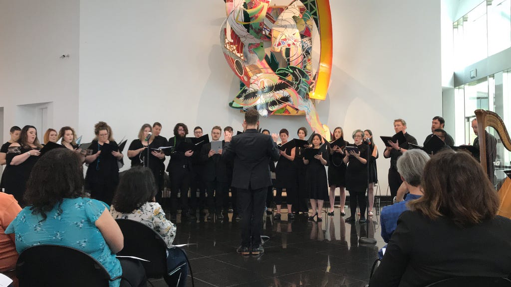 Project participants sing for a small audience at a gallery or museum