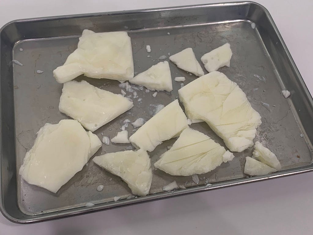 Pieces of frozen store-bought yogurt broken into chunks and placed on a metal tray.