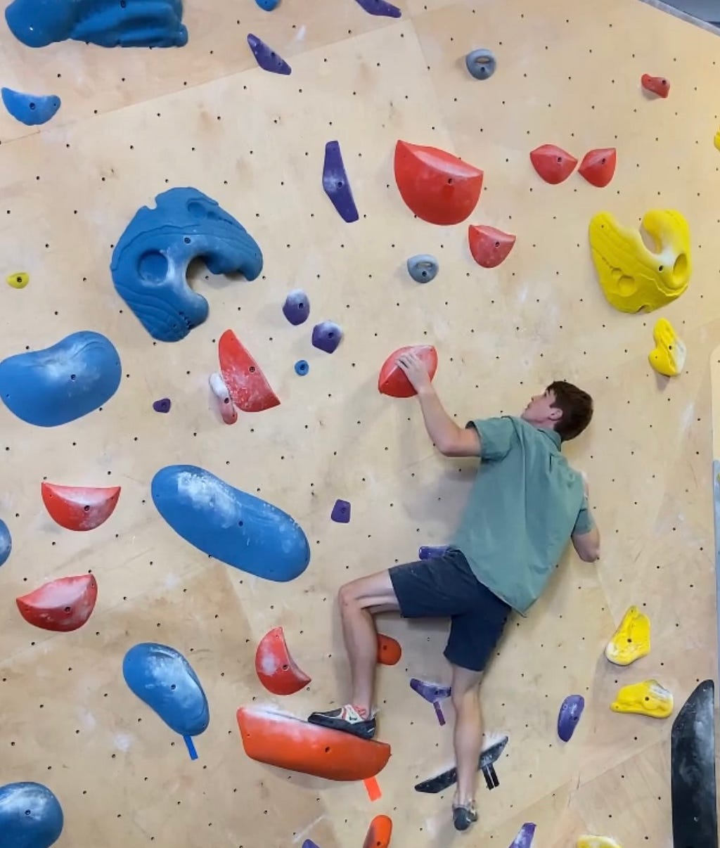 Spencer Morris climbing an indoor bouldering route