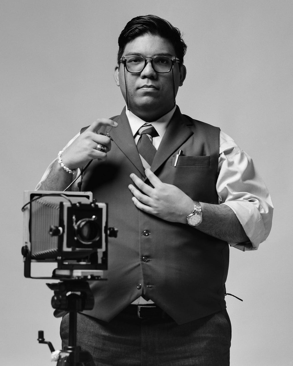 Emillio standing, holding the flash controller for his Analog camera that stands across him.