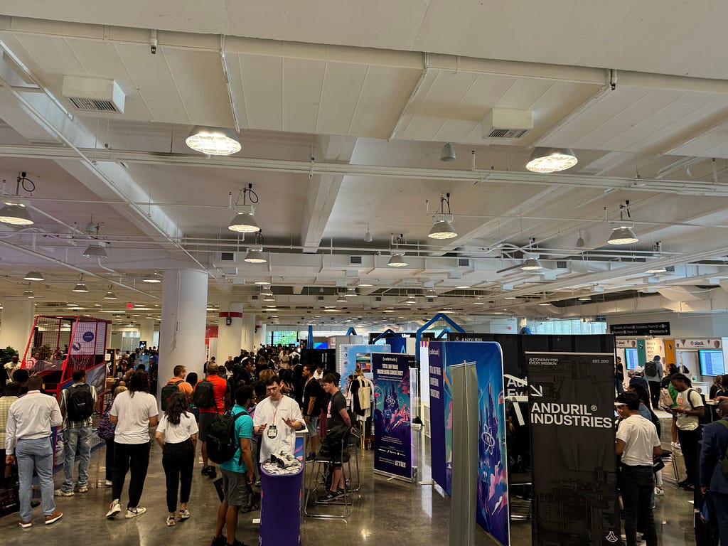 Conference attendees explore a large area with multiple vendor booths.