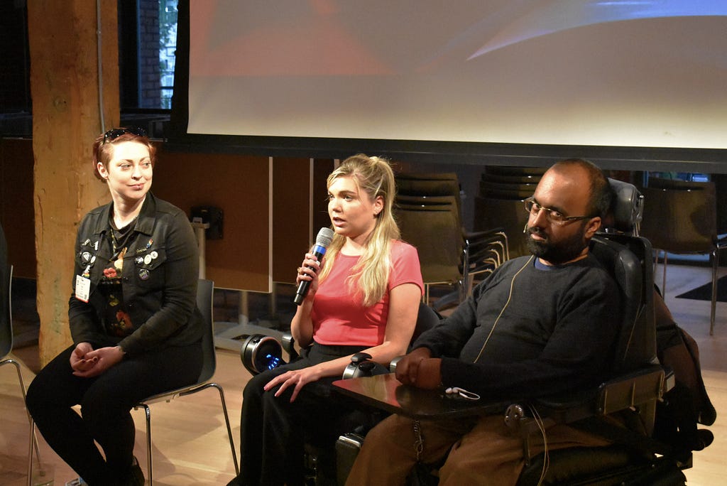 Iris on the left in black, Sunday Parker in the middle holding a microphone, and Srin Madipalli on the right.