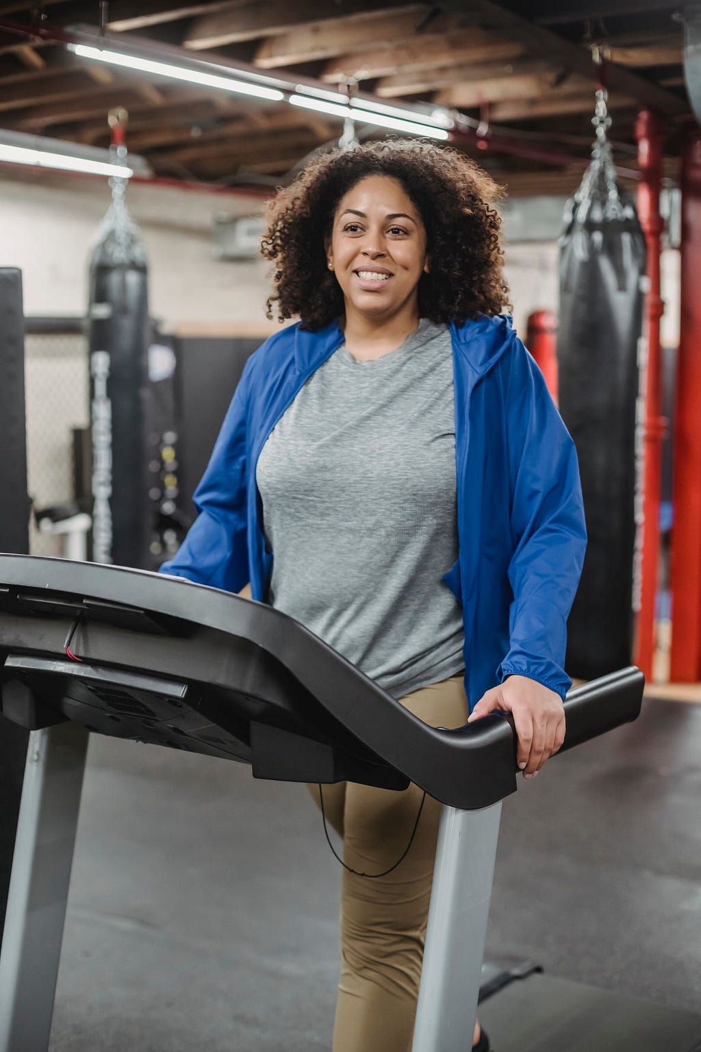 Photo of a woman walking on an indoor treadmill and smiling