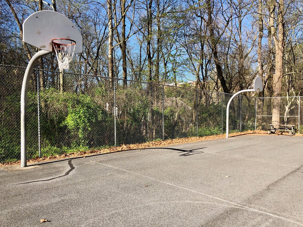 Photo of two basketball courts, one with the rims removed
