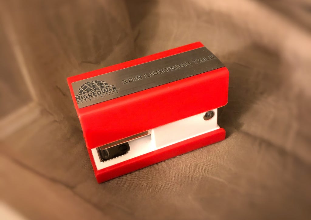 Miniature red stapler with “2019 Lightning Talk” and High Ed Web Association logo on top.