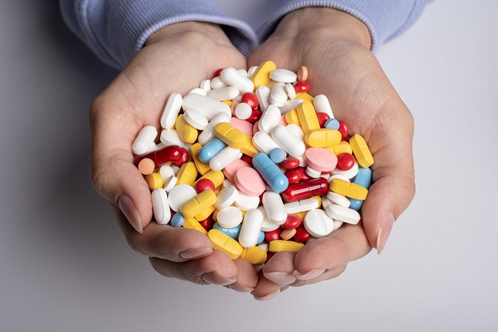 Woman hands full of various pills