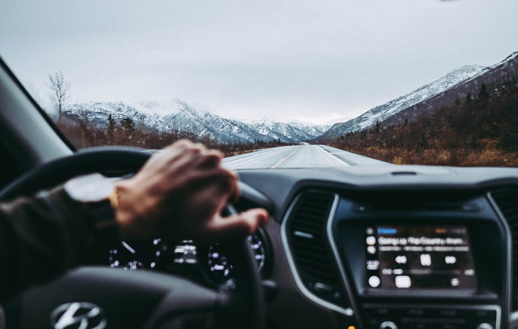 Person driving a car with mountains in the background