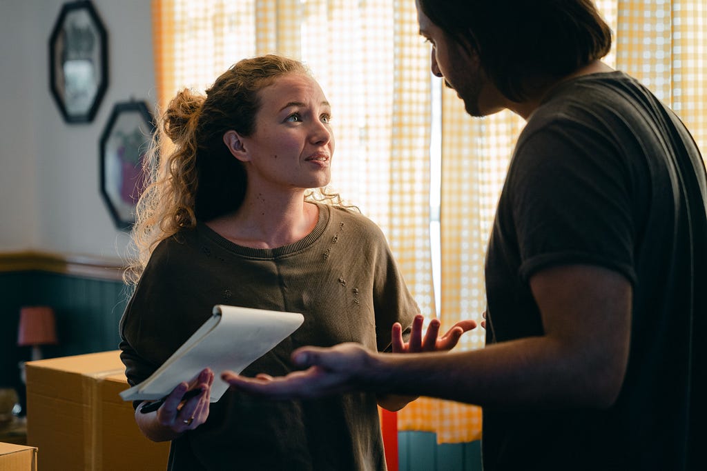 Worried couple with a notebook looking at each other.