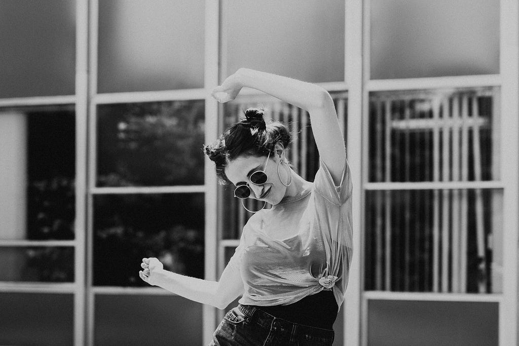 Woman in sunglasses, dancing.
