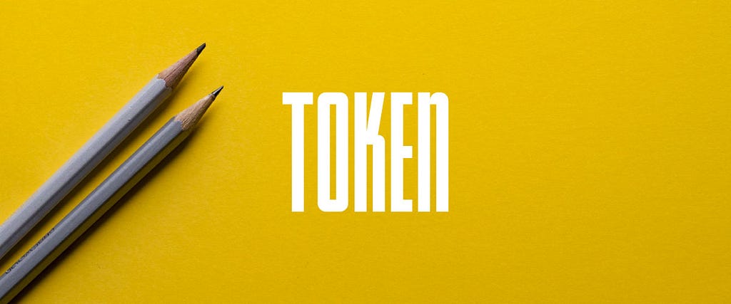 The Token logo on top of a photo of two gray pencils on a yellow background.