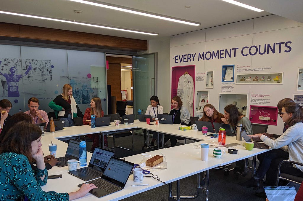 A group of people sat around a table with laptops