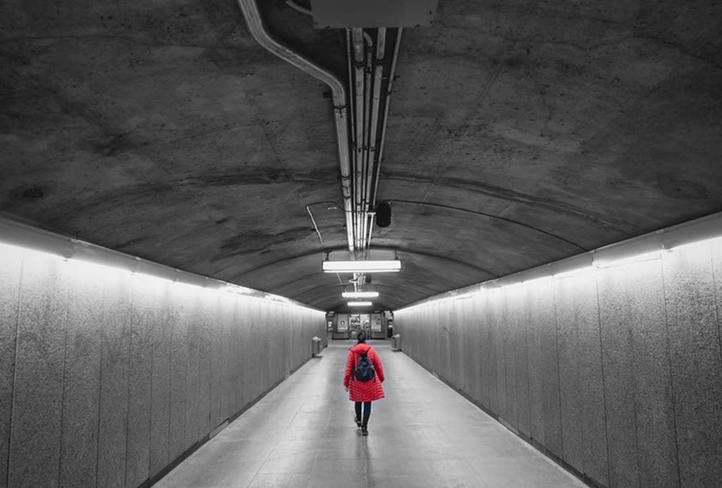 Person wearing red jacket and backpack in a subway