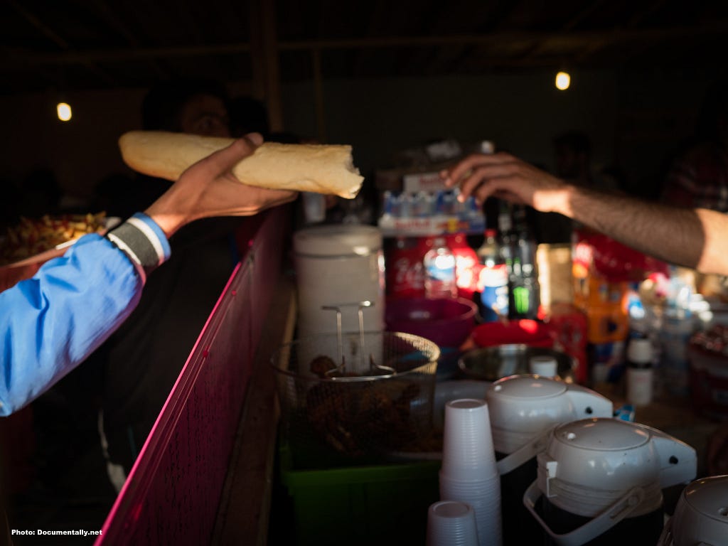 Two hands meet in this moving photograph that was captured in the camp. A baguette is in one hand, and another hand extends to take it. The goodwill in the gift is obviously meant with gratitude, and the setting in the camp emphasizes its value given the difficult circumstances. An image taken by Christian Payne AKA documents. We have the Calais migrant camp in France.