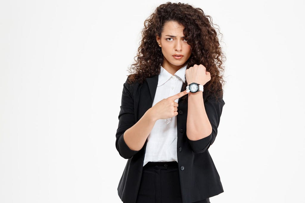 woman pointing at her wristwatch, signal that it’s time to look for a new job