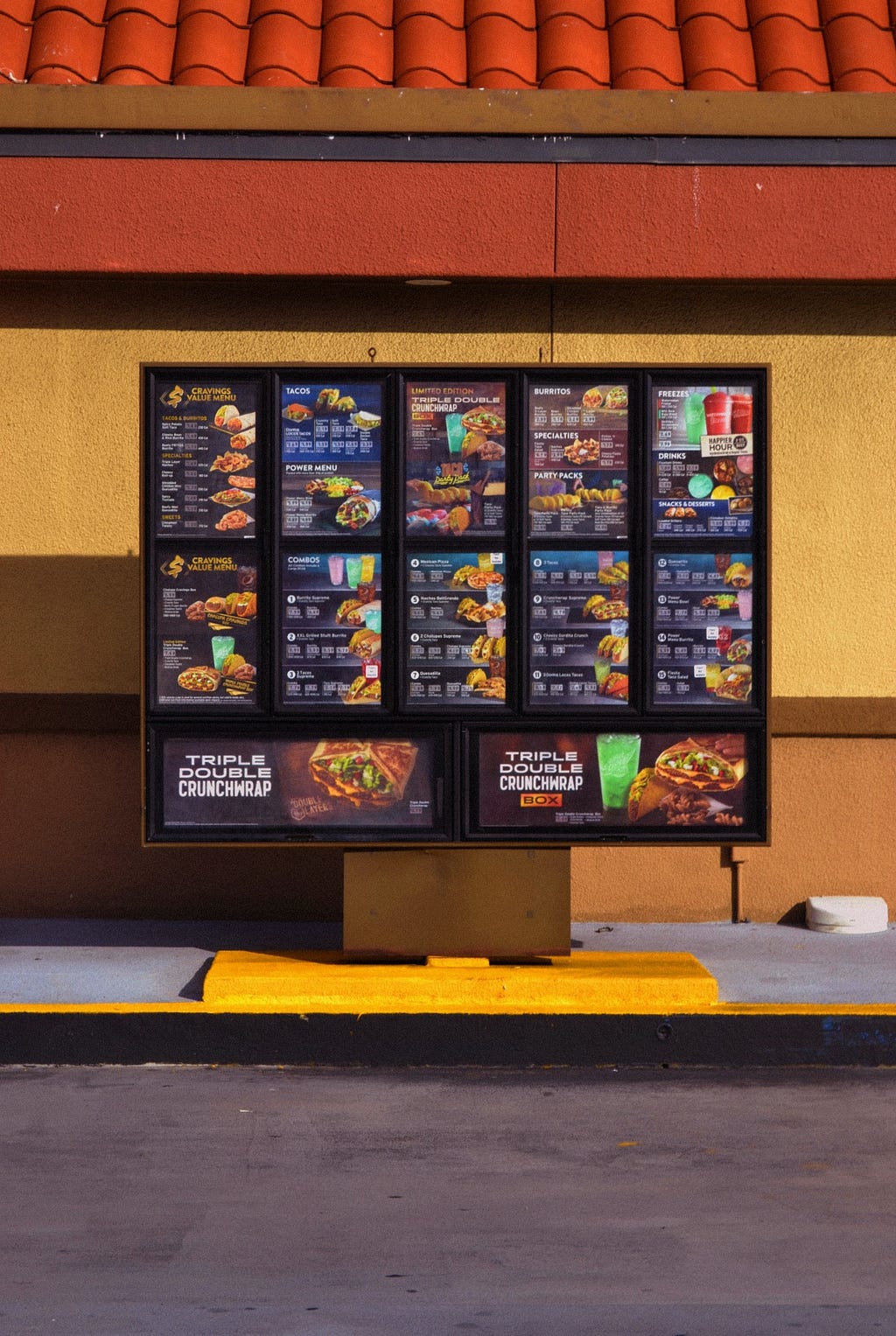 A Taco Bell drive thru menu is framed in the center of an orange building.