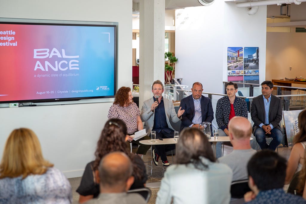 Four people facing a crowd for a panel discussion.