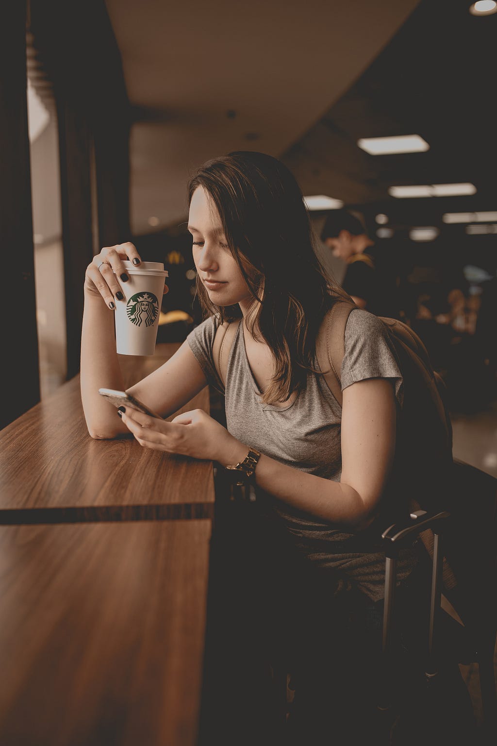 A woman drinking Starbucks and checking her text messages on iPhone