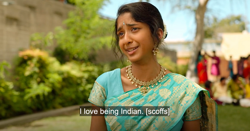 An image of Devi at Ganesh Puja with dialogue subtitled “I love being Indian. [scoffs]”