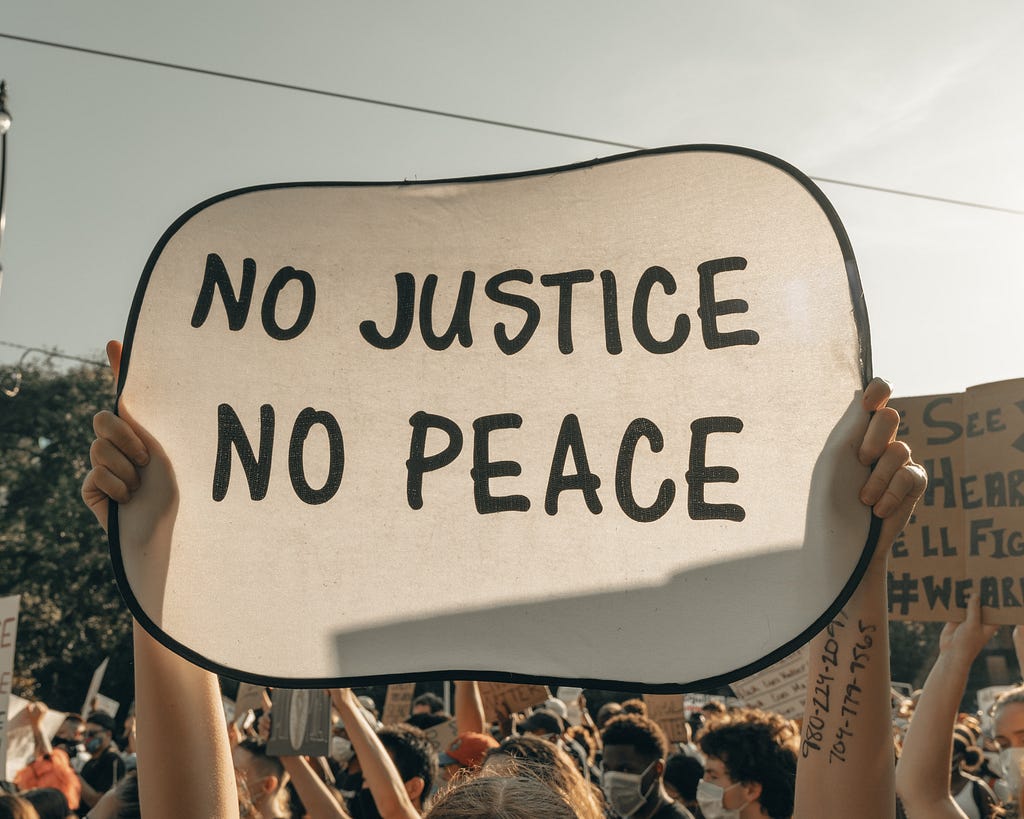 A banner with the words No Justice No Peace, Nyk, Medium