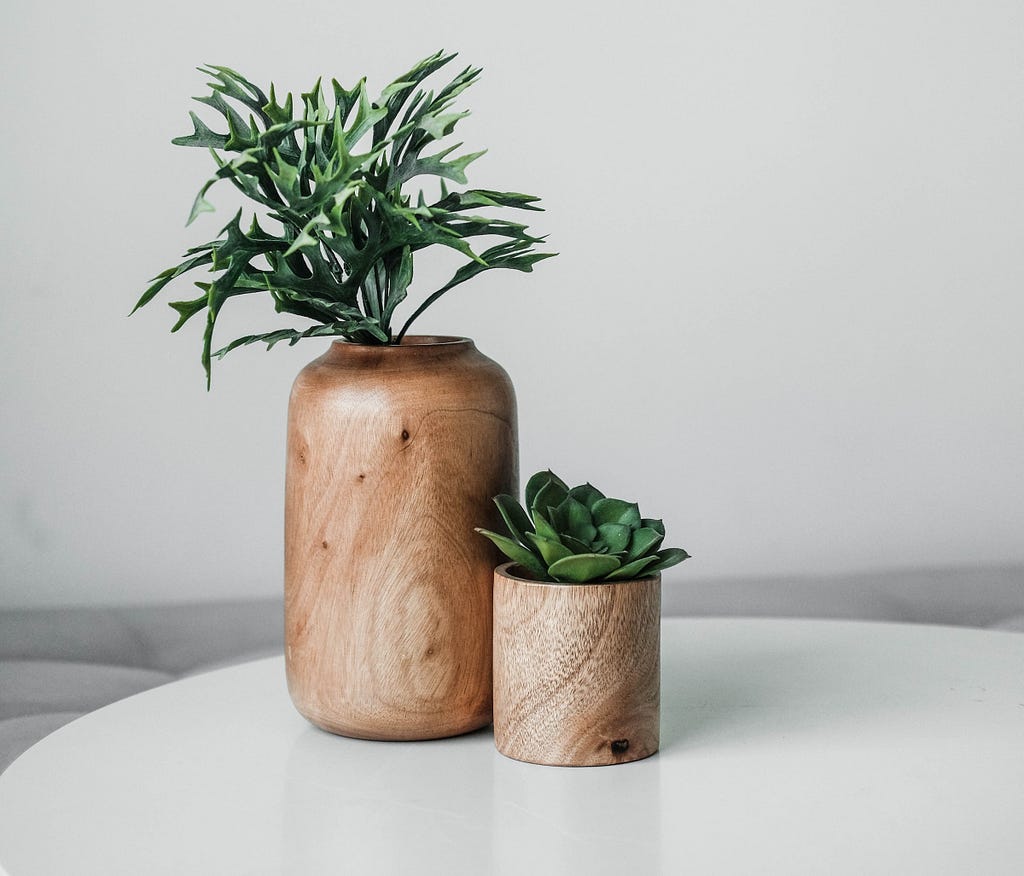 A photo of a small flowerpot next to a big flowerpot, they are both wooden