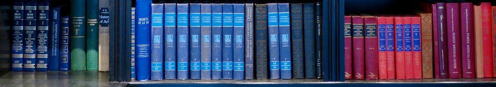 Row of older books, with covers in Blue, Red and Pink.