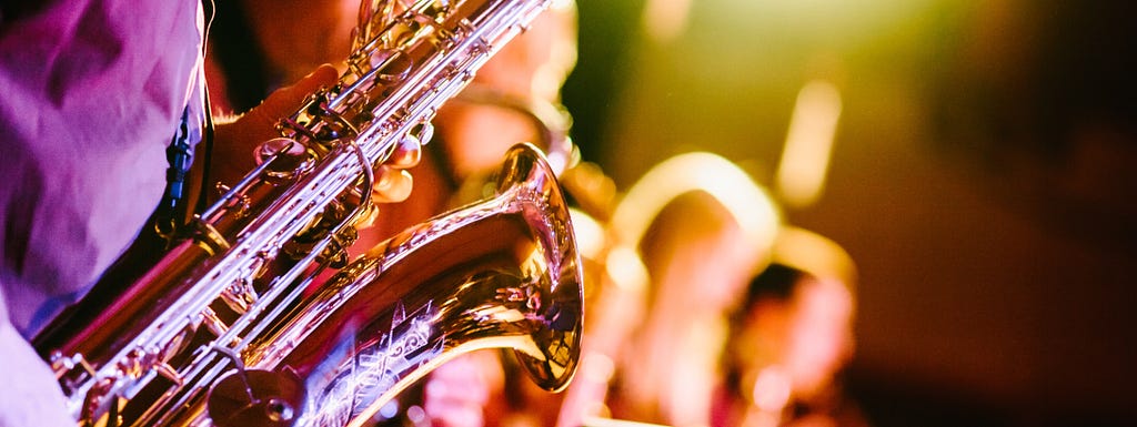 Saxophone player and backing vocal singers — Photo by Jens Thekkeveettil on Unsplash
