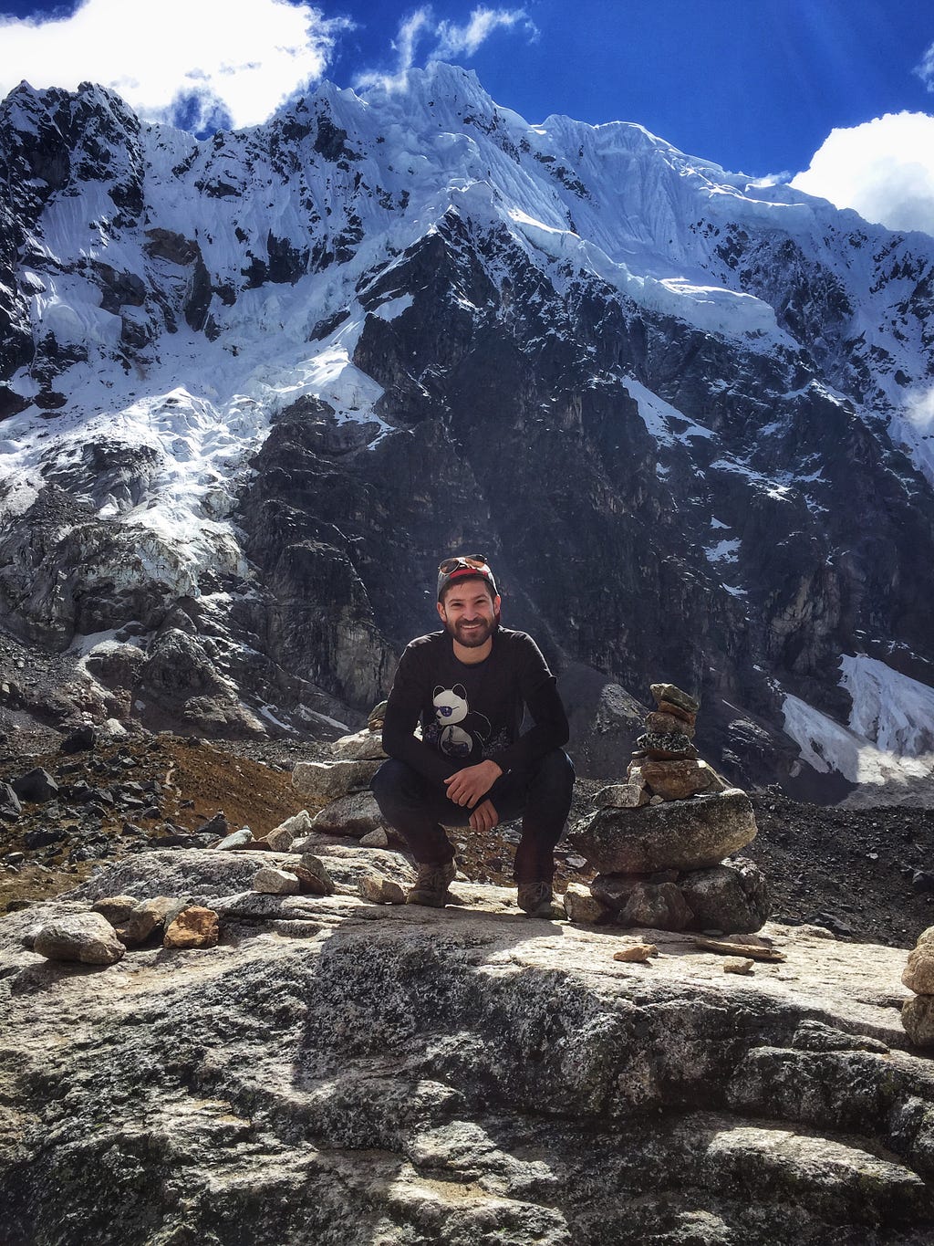 Gilad, traveler & creator of Anxious & Abroad, at the Salkantay Trek in Peru with mountains, glaciers & snow in the distance.