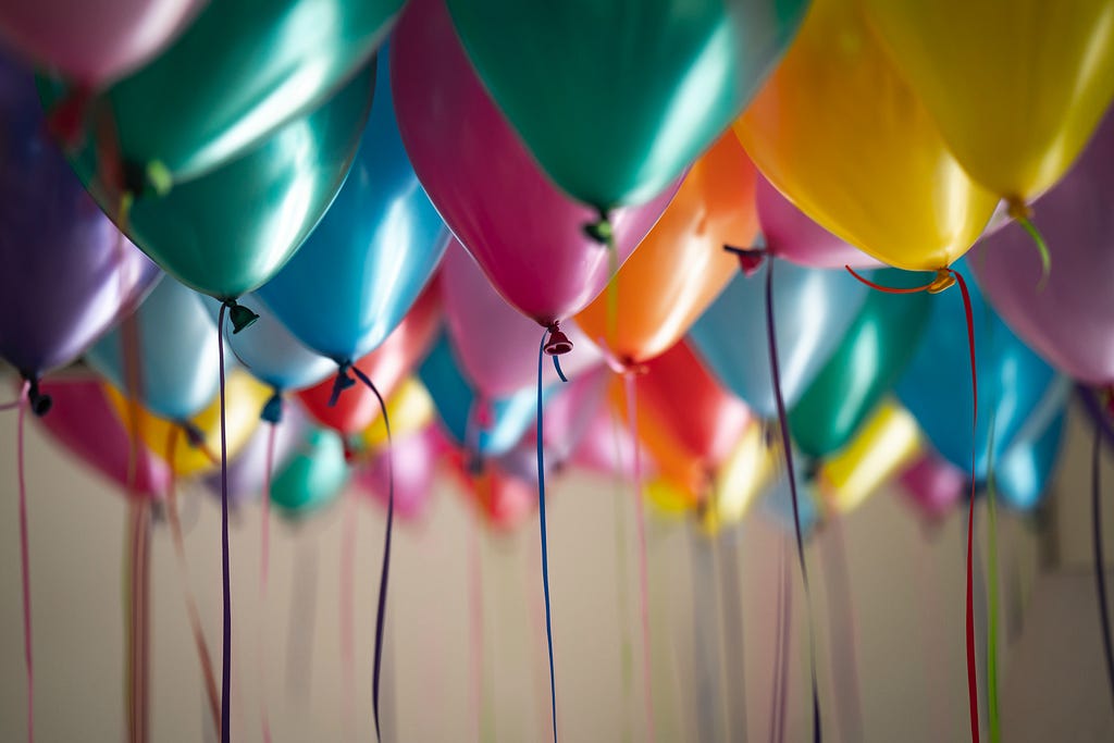Multicoloured baloons floating with ribbons.