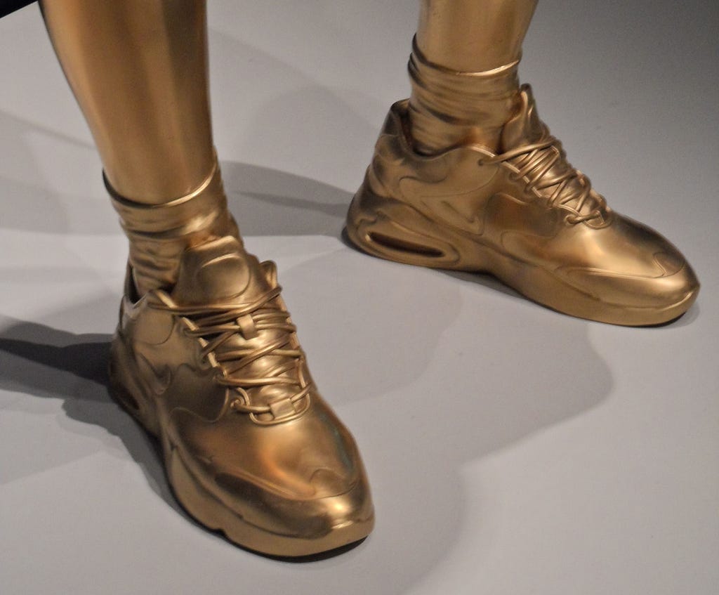 Golden pair of sneakers by Thomas J Price, As Sounds Turn To Noise.