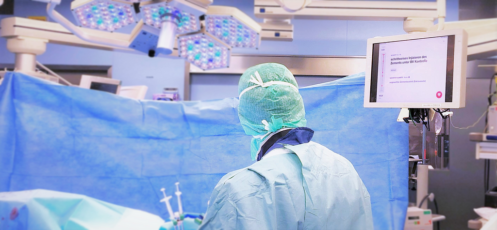 A surgeon looking at the Nodus Medical application on a screen in an operating room while performing a surgery.