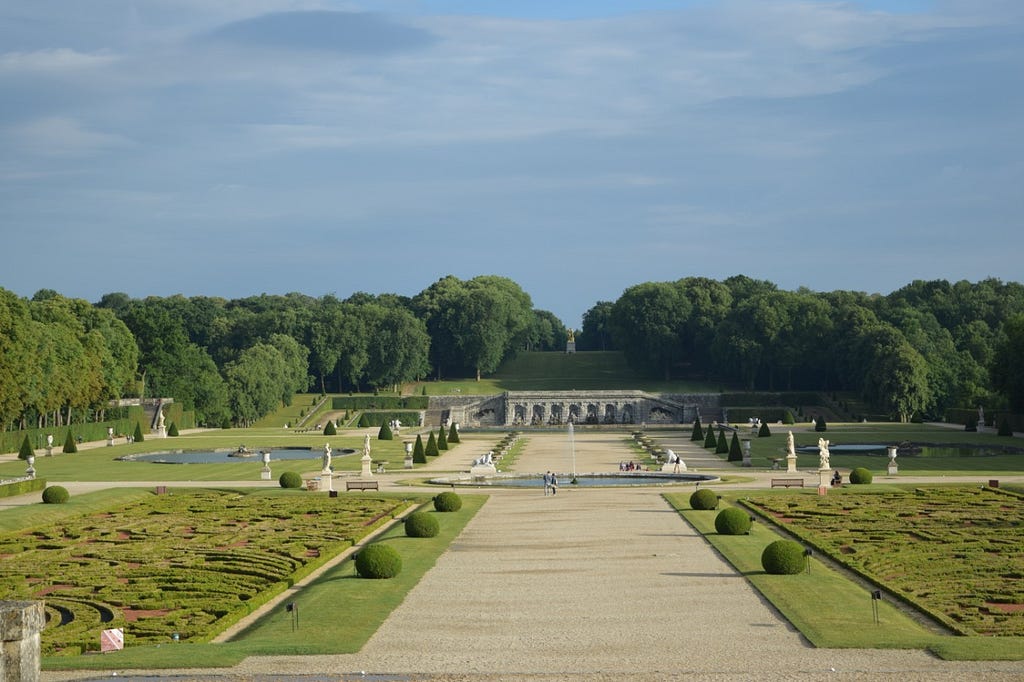 The grounds of the Château de Vaux-le-Vicomte (parterres, basins, grotto, statues) on a summer night.
